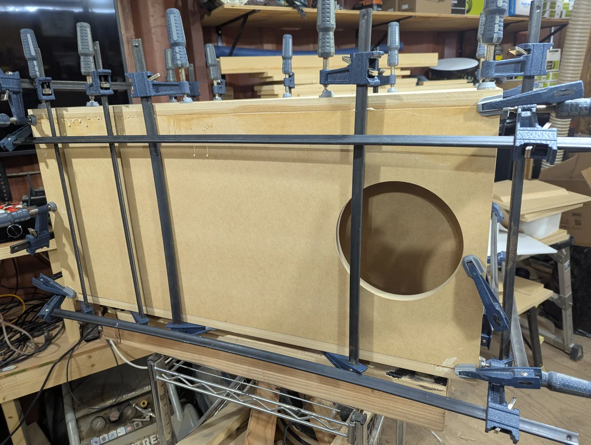 Wide MDF sealed enclosure baffle panel with 8-inch woofer cutout being glued and clamped for the Wanstreet Scottsdale dual-amplified tower speaker build