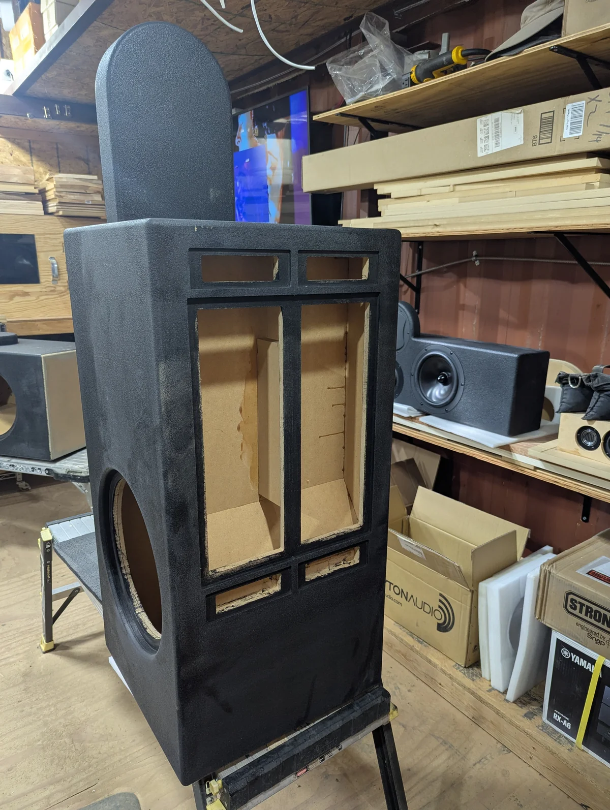 Rear panel of Wanstreet tower speaker cabinet with Duratex textured finish showing dual amplifier mounting openings with internal amp chamber structure visible, and 12-inch subwoofer driver opening on the side of the base enclosure