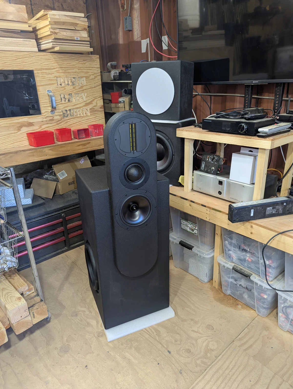 Completed Wanstreet tower speaker with Duratex finish showing all drivers installed — ribbon tweeter, dome mid, 8-inch woofer in pill-shaped upper section and 12-inch subwoofer in base enclosure — fully assembled in workshop
