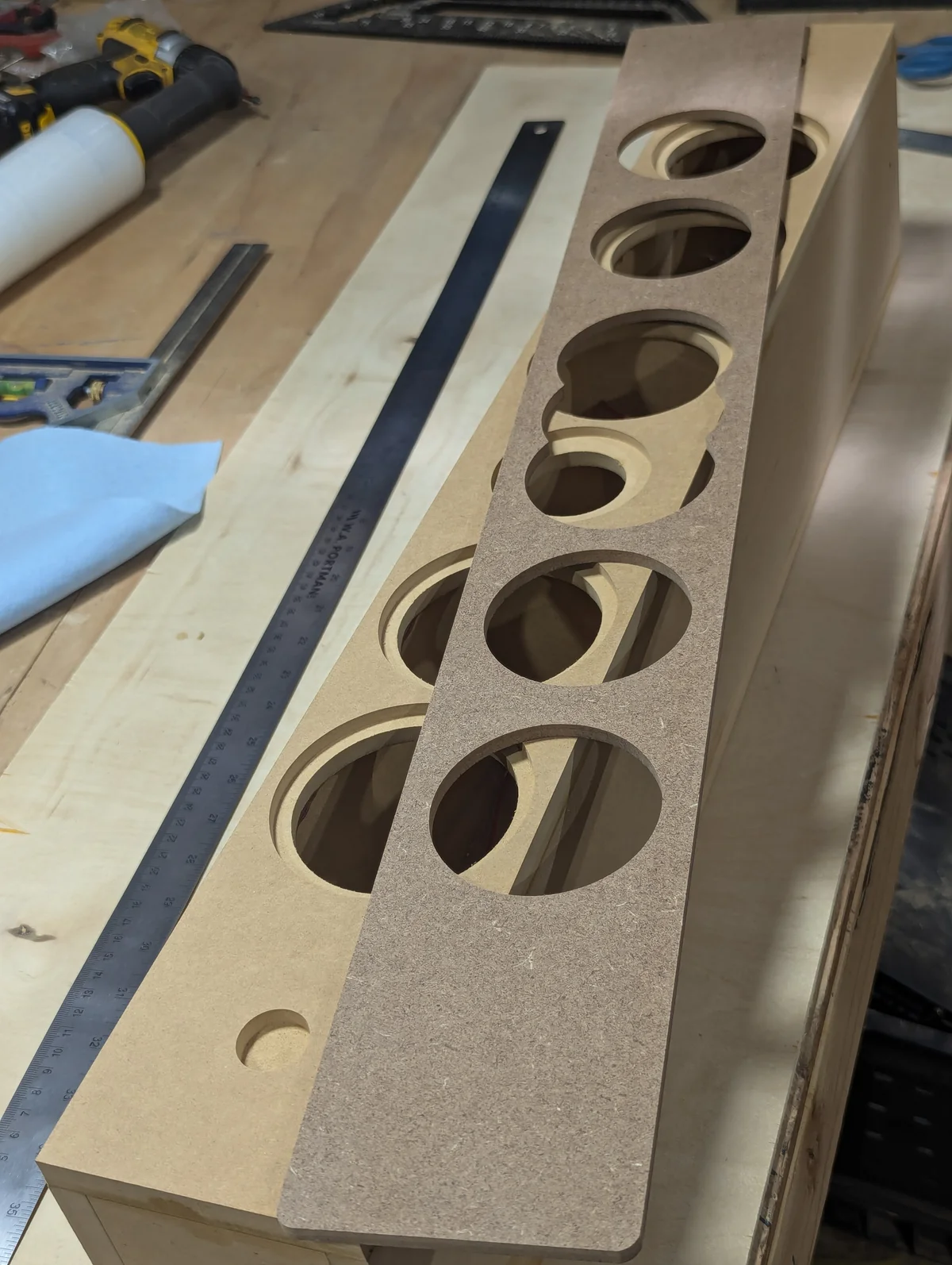 CNC machined MDF center channel inner baffle panel showing six recessed driver pockets for AMT tweeter, 3-inch mid, and four 3-inch woofers with ruler showing slim cabinet depth for the Lafferty Prescott Valley custom home audio build