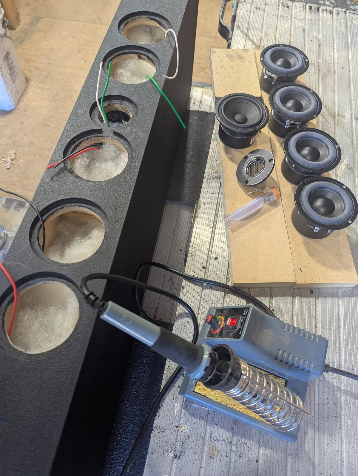 Lafferty center channel cabinet with Duratex finish and six driver wiring leads pulled through cutouts alongside AMT tweeter, 3-inch mid, and four 3-inch woofer drivers staged on workbench with soldering iron for a custom Prescott Valley home audio build