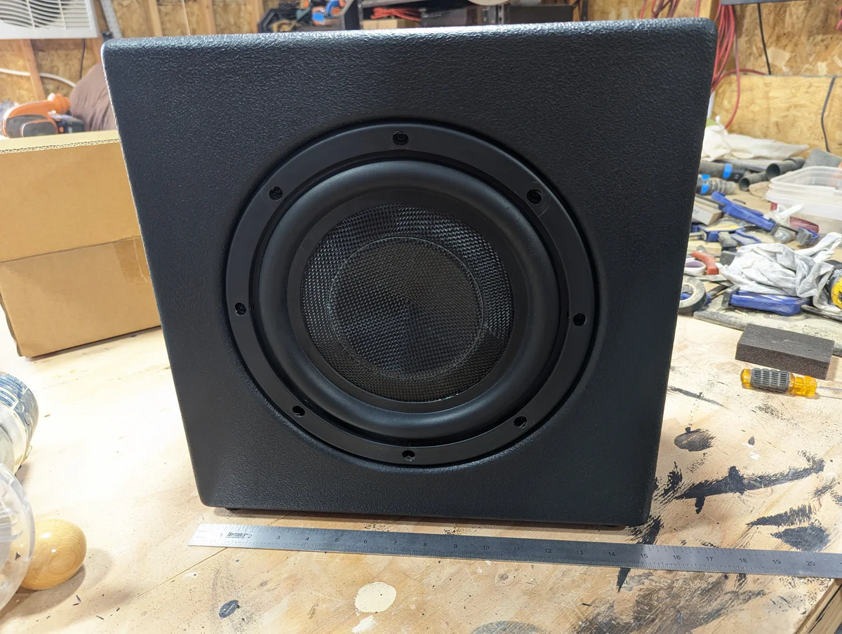 Completed compact custom subwoofer cabinet with Duratex textured finish and flush-mounted 10-inch woofer driver installed on workbench with ruler showing compact footprint for the Lafferty Prescott Valley 500 watt home audio build